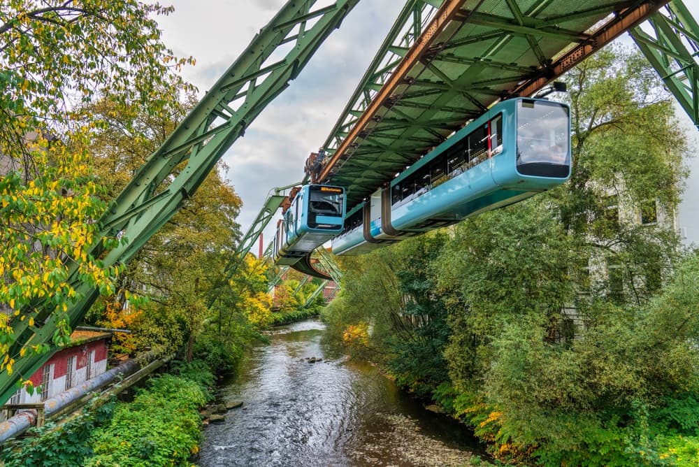 Wuppertaler Schwebebahn über der Wupper zwischen grünen Uferbäumen